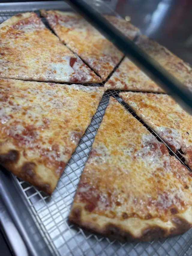 New York style cheese pizza cut into slices on a cooling rack