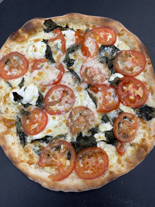 White tomato basil pizza with sliced tomatoes and fresh basil