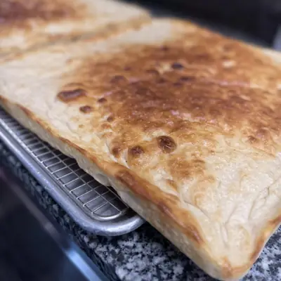 A golden Sicilian style pizza in its pan