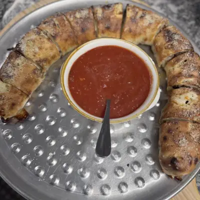 A ring shaped family stromboli around a cup of marinara